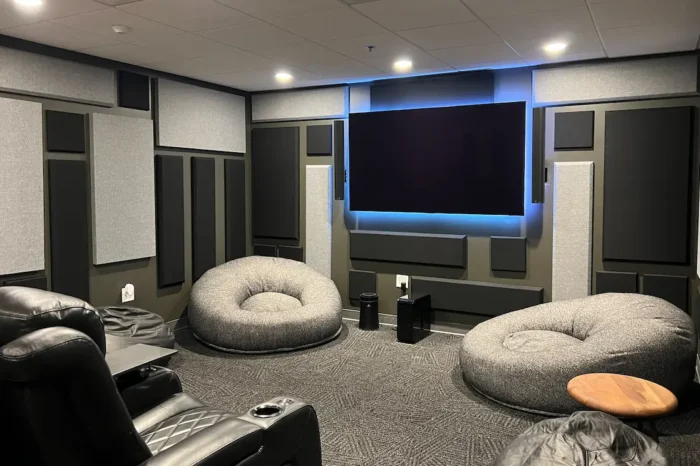 Premium media room with acoustic panels, large wall-mounted display, lounge seating, and integrated AV equipment installed by Macrotek.