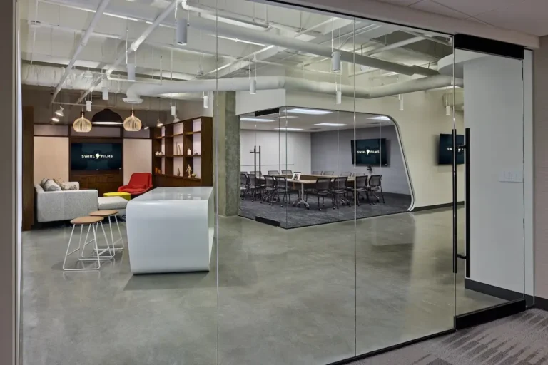 Modern office with glass-walled conference room and media lounge featuring multiple displays installed by Macrotek for Swirl Films.
