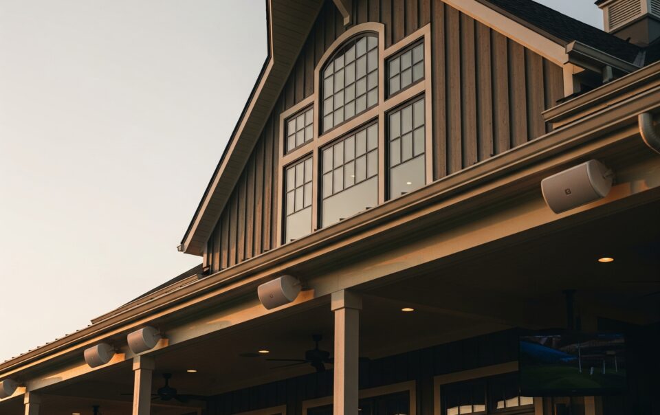Modern country club exterior with integrated outdoor AV system and mounted speakers at sunset